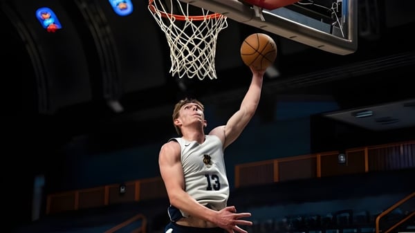 Ein Basketballspieler springt zum Korbwurf auf dem Spielfeld der Royal Crown School.