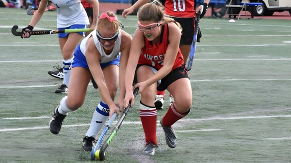 Zwei Schülerinnen der Royal High School spielen ein Feldhockeyspiel und kämpfen um den Ballbesitz.