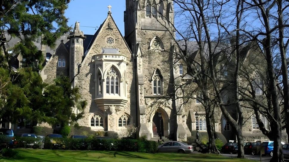 Die Royal High School mit einer großen steinernen Kirche im gotischen Stil und parkenden Autos im Vordergrund.