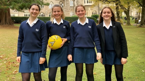 Vier Schülerinnen in Schuluniformen stehen gemeinsam auf dem Campus der Royal High School im Grünen.