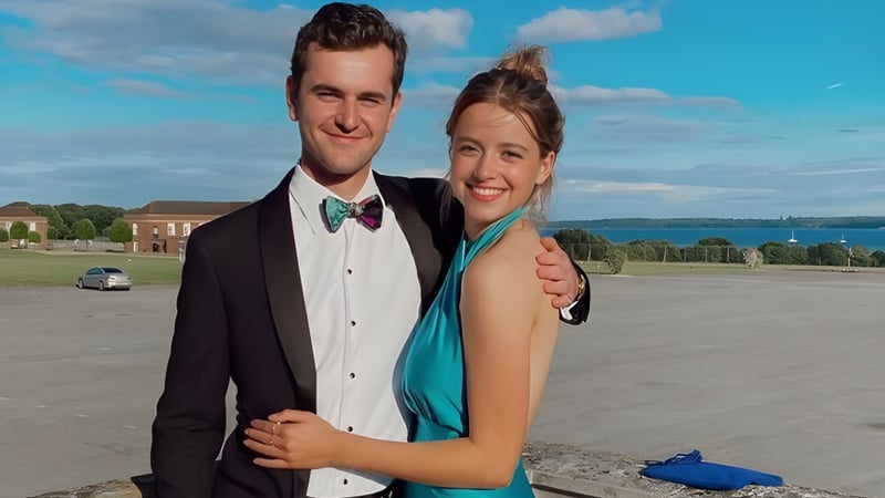 Ein Paar steht vor einer landschaftlichen Kulisse mit Wasser und Gebäuden auf dem Gelände der Royal Hospital School.