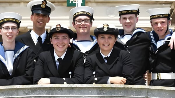 Eine Gruppe von Schülern in Marineuniformen steht vor einem Gebäude mit verzierter Architektur auf dem Campus der Royal Hospital School.