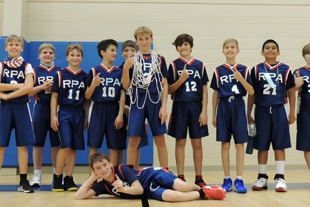 Eine Gruppe von Schülerinnen und Schülern der Royal Palm Academy posiert in ihren blauen Basketball-Uniformen in einer Turnhalle.