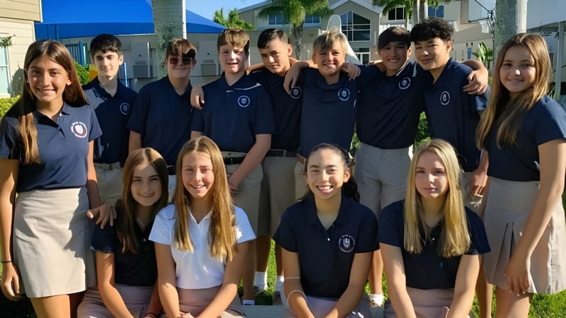 Eine Gruppe Schüler der Royal Palm Academy posiert gemeinsam vor einem Gebäude mit Palmen im Hintergrund.