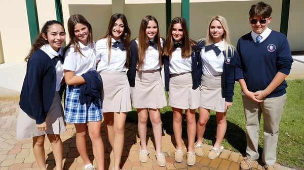 Eine Gruppe Schülerinnen und Schüler der Royal Palm Academy steht draußen vor einem Gebäude auf einem gepflasterten Platz.