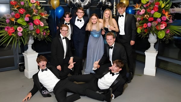 Eine Gruppe formell gekleideter Personen posiert bei einer Veranstaltung mit Blumenarrangements auf dem Campus der Royal Russell School.