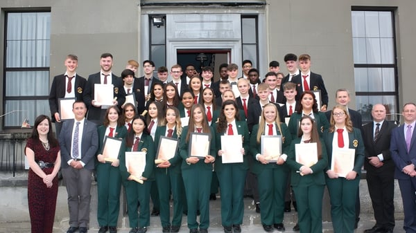 Eine große Gruppe von Schülern der Royal School Cavan steht in formeller Kleidung vor dem markanten Schulgebäude.