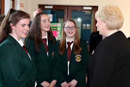 Schüler der Royal School Cavan unterhalten sich im Schulflur in ihren Schuluniformen mit grünen und schwarzen Roben.