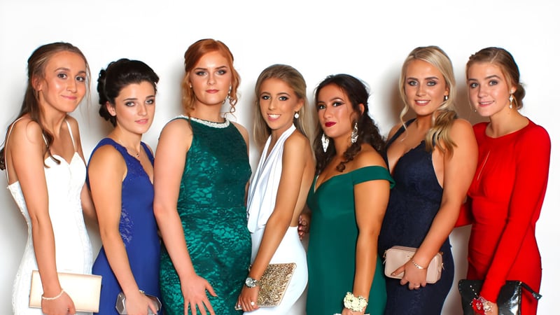 Sechs Schülerinnen der Royal School Dungannon posieren in farbenfrohen Kleidern vor einem weißen Hintergrund.