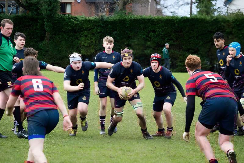 Eine Gruppe von Rugby spielenden Schülerinnen und Schülern auf dem Spielfeld der Royal School.