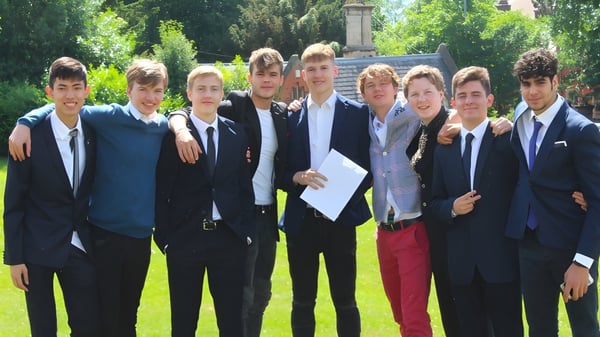 Eine Gruppe von Schülern der Royal School Wolverhampton steht in formeller Kleidung im Grünen vor einem Denkmal.