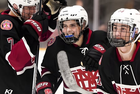 Drei Eishockeyspieler in Uniform auf dem Eis, einer trägt ein Trikot mit den Buchstaben A und M, auf dem Eisfeld der Royal Vale High School.