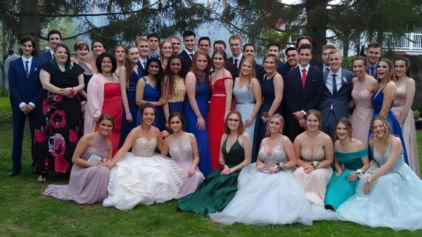 Eine große Gruppe von Schülerinnen und Schülern der Russell High School posiert in formeller Kleidung draußen vor Bäumen für ein Gruppenfoto.