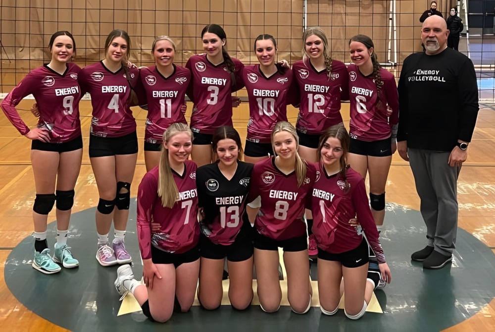 Eine Gruppe von Volleyballspielerinnen der Rutland Senior Secondary School posiert zusammen mit ihrem Trainer in der Sporthalle.