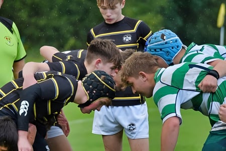 Eine Gruppe von rugbyspielenden Schülerinnen und Schülern der Rydal Penrhos School ist beim Scrum auf dem Rasenfeld zu sehen.