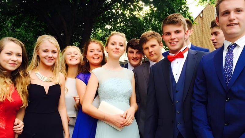 Eine Gruppe von Schülerinnen und Schülern der Ryde School steht im Freien vor grünen Bäumen.