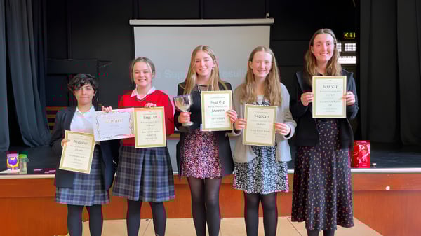 Eine Gruppe junger Schülerinnen der Rye St. Antony School hält Zertifikate und Auszeichnungen vor einer Bühne.