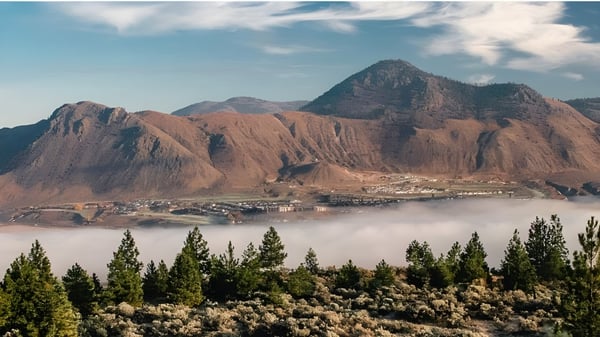 Blick auf schneebedeckte Berge und ein bewaldetes Tal in der Nähe der Sa-Hali Secondary School.