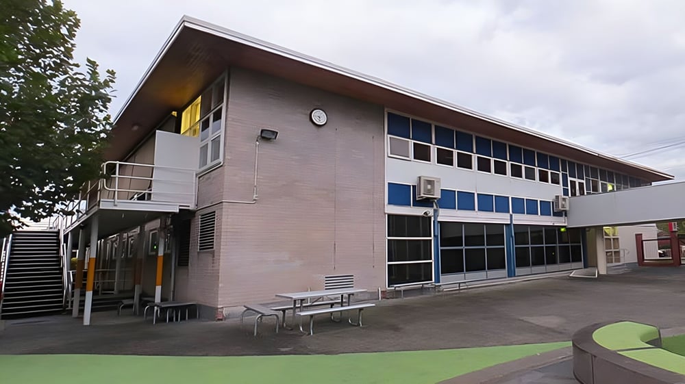 Das moderne mehrstöckige Gebäude des Sacred Heart Girls' College in Hamilton mit großen Fenstern und überdachtem Sitzbereich im Freien.