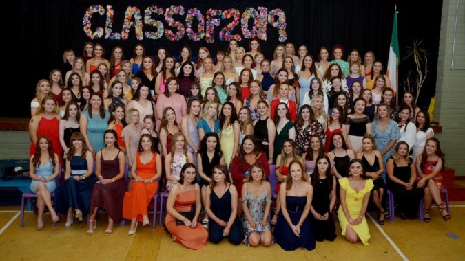 Eine große Gruppe Schülerinnen der Sacred Heart School posiert gemeinsam in der Turnhalle vor dem Schriftzug Class of 2013.