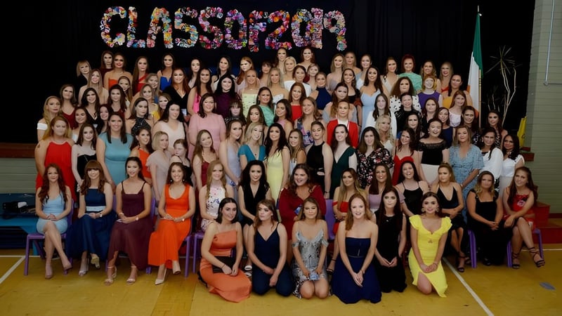 Eine große Gruppe Schülerinnen der Sacred Heart School posiert in bunten Kleidern in einer Sporthalle vor dem Schriftzug CLASSOF2020.