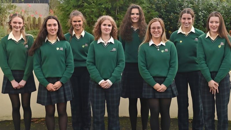 Eine Gruppe von Schülerinnen der Sacred Heart School steht im grünen Schuluniform draußen auf einer Wiese vor Bäumen und einem Gebäude.