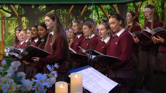 Schüler der Sacred Heart Secondary School in Tullamore treten gemeinsam im Freien vor grüner Kulisse auf.