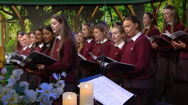 Schüler der Sacred Heart Secondary School in Tullamore stehen gemeinsam im Grünen und singen im Chor.