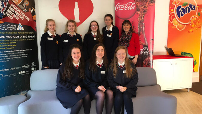 Eine Gruppe von Schülerinnen der Sacred Heart Secondary School in Schuluniform posiert vor Coca-Cola und Fanta Werbedisplays.