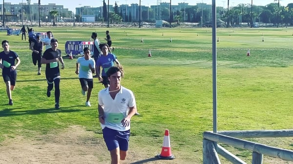 Eine Gruppe von Fußballspielern steht auf dem Sportplatz des Sage College vor Gebäuden im Hintergrund.