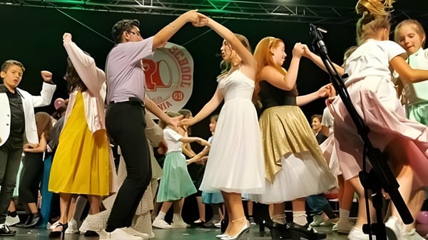 Eine Gruppe von Schülern feiert gemeinsam auf der Bühne des Sage College mit erhobenen Armen.