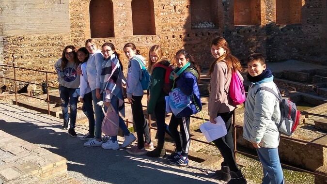 Eine Gruppe Schüler vor dem historischen Stein-Gebäude mit Bogenfenstern auf dem Campus des Sage College.