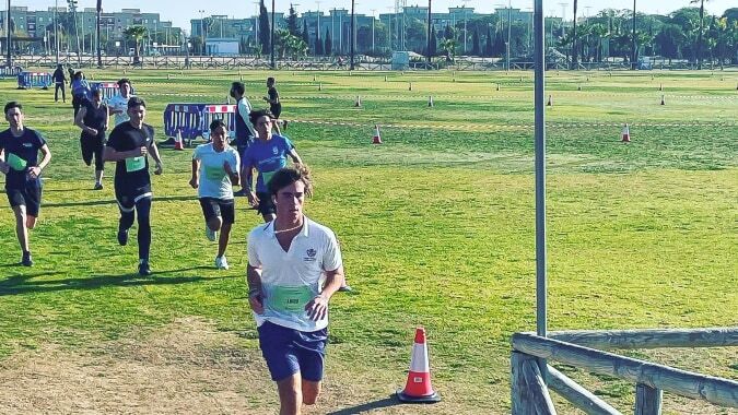 Eine Gruppe Sportler steht auf dem Sportplatz des Sage College umgeben von Gebäuden.