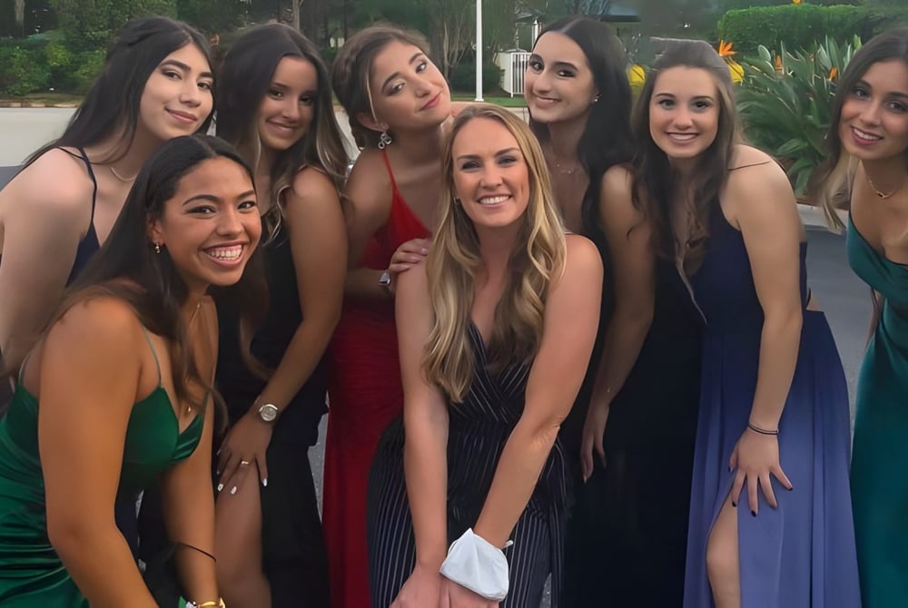 Eine Gruppe junger Frauen in bunten Kleidern posiert draußen auf dem Campus der Sagemont School.