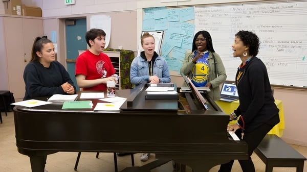 Schüler der Sagemont School versammeln sich um ein Klavier im Klassenzimmer für eine gemeinsame Besprechung.