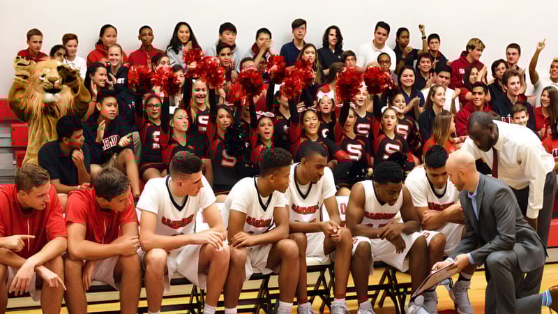 Eine Gruppe Schülerinnen und Schüler der Sagemont School versammelt sich in einer Sporthalle in roten und weißen Uniformen.