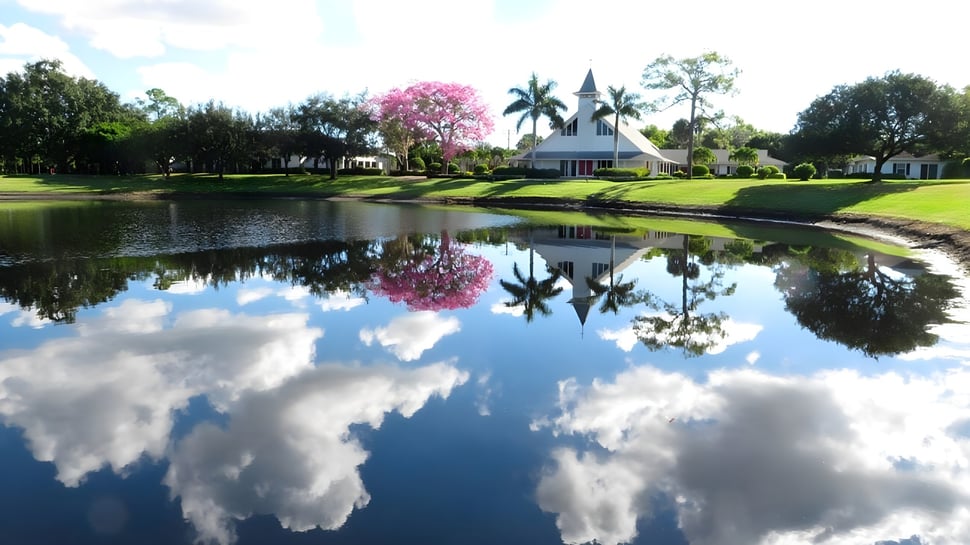 Ein ruhiger Teich mit blühendem pinken Baum spiegelt die Landschaft auf dem Campus der Saint Andrews School wider.