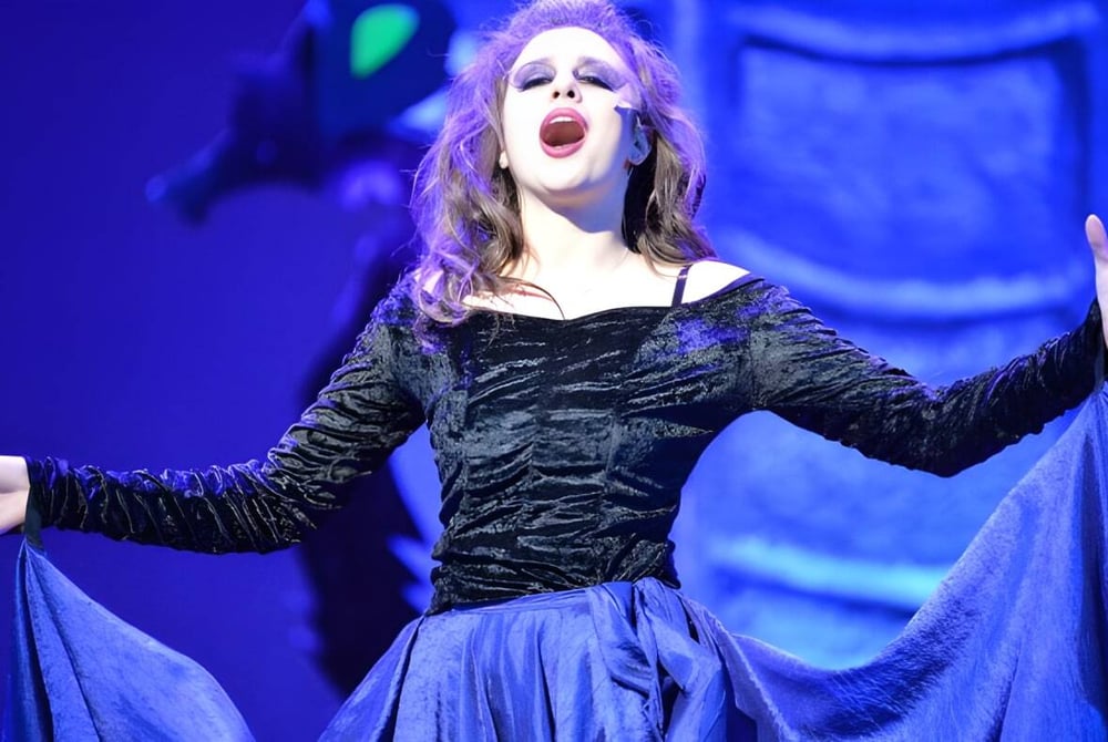 Eine Schülerin von Saint Anthony's High School führt auf der Bühne vor blauem Hintergrund auf.