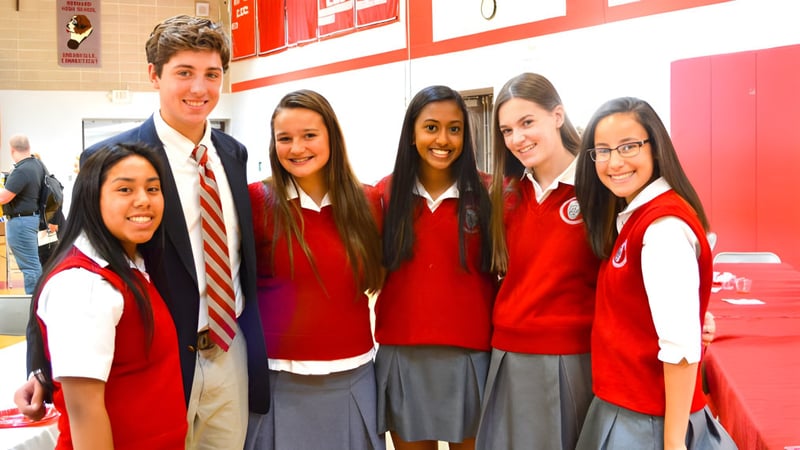 Eine Gruppe von Schülerinnen und Schülern in roten Uniformen steht zusammen im Schulgebäude der Saint Bernard School.