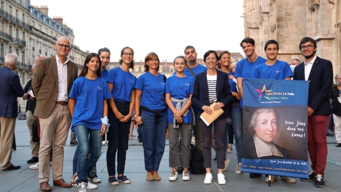 Eine Gruppe von Schülerinnen und Schülern steht mit einem Banner vor einem Gebäude auf dem Gelände der Saint-Genès La Salle.