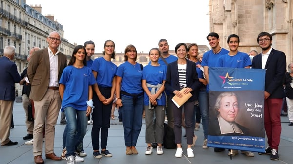 Eine Gruppe Schülerinnen und Schüler der Saint-Genès La Salle steht vor einem Gebäude mit einem Banner für eine Veranstaltung.