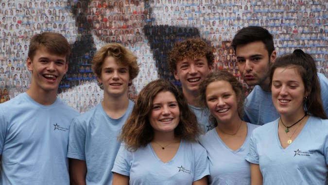 Eine Gruppe Schüler der Saint-Genès La Salle steht vor einer bunten Ziegelwand und lächelt.