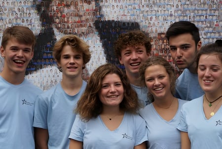 Eine Gruppe Schülerinnen und Schüler der Saint-Genès La Salle steht vor einem bunten Wandgemälde.