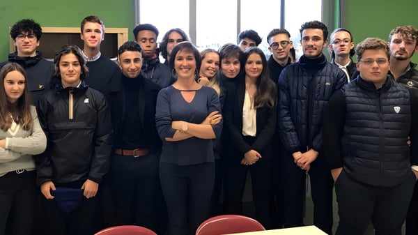 Eine Gruppe von Schülerinnen und Schülern steht in einem Raum mit grüner Wand auf dem Campus der Saint-Genès La Salle.
