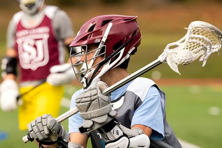 Ein Lacrosse-Spieler der Saint James School steht mit Helm und Schläger auf dem Spielfeld.