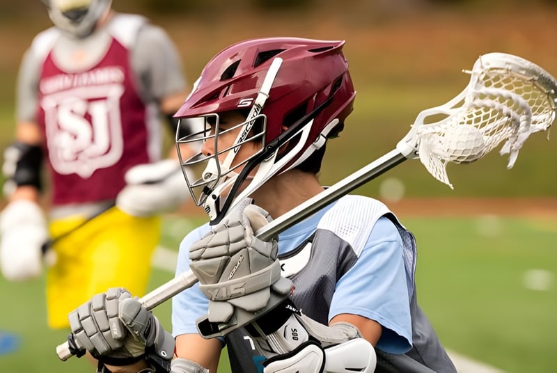 Ein Lacrosse-Spieler der Saint James School steht mit Helm und Schläger auf dem Spielfeld.