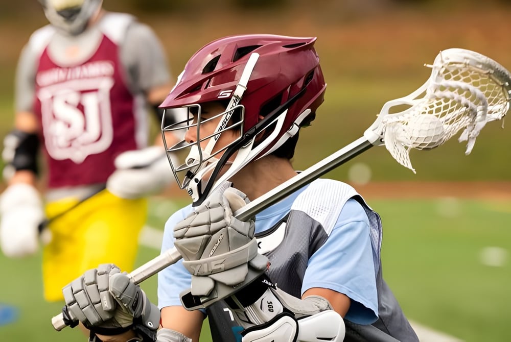 Ein Lacrosse-Spieler der Saint James School steht mit Helm und Schläger auf dem Spielfeld.