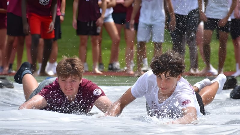 Zwei Personen liegen in einer Wasserpfütze vor einer Menschenmenge auf dem Gelände der Saint James School.