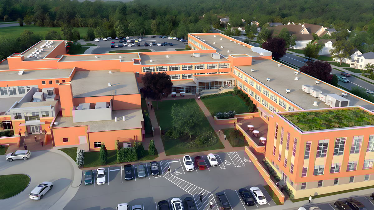 Das mehrstöckige Gebäude der Saint Johns High School mit orangenem Dach steht auf einem Parkplatz vor einem bewaldeten Hintergrund.