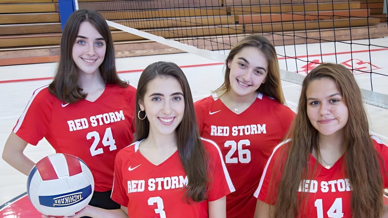 Vier Schülerinnen der Saint Johns High School tragen rote Trikots mit Red Storm und stehen gemeinsam in einer Sporthalle.